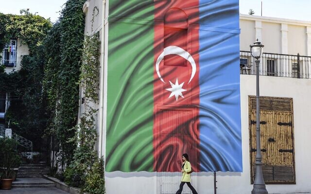 A woman walks past a building with a painting of the Azerbaijani flag on its wall in Baku on October 14, 2020, amid the ongoing military conflict between Armenia and Azerbaijan over the breakaway Nagorno-Karabakh region. (TOFIK BABAYEV / AFP) A woman walks past a building with a painting of the Azerbaijani flag on its wall in Baku on October 14, 2020, amid the ongoing military conflict between Armenia and Azerbaijan over the breakaway Nagorno-Karabakh region. (TOFIK BABAYEV / AFP)