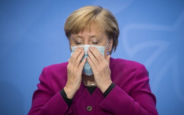 German Chancellor Angela Merkel puts on her a mask at the end of a press conference following a meeting of states' leaders on the coronavirus situation in Berlin on October 14, 2020. (STEFANIE LOOS / various sources / AFP) German Chancellor Angela Merkel puts on her a mask at the end of a press conference following a meeting of states' leaders on the coronavirus situation in Berlin on October 14, 2020. (STEFANIE LOOS / various sources / AFP)