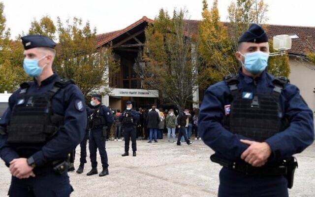 French police officers stand as adults and children gather in front of flowers displayed at the entrance of a middle school in Conflans-Sainte-Honorine, on October 17, 2020. (Bertrand GUAY / AFP) French police officers stand as adults and children gather in front of flowers displayed at the entrance of a middle school in Conflans-Sainte-Honorine, on October 17, 2020. (Bertrand GUAY / AFP)