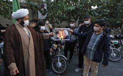 Iranians burn a picture of French President Emmanuel Macron and Prime Minister Benjamin Netanyahu during a protest outside the French embassy in Tehran against comments by Macron defending cartoons of the Prophet Mohammed, on October 28, 2020 (ATTA KENARE / AFP)