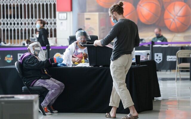 A voter (R) walks toward an election official who is wearing a face shield, mask and gloves at a Vote Center located at the Staples Center on the first weekend of early in-person voting on October 25, 2020 in Los Angeles, California. (Mario Tama/Getty Images/AFP) A voter (R) walks toward an election official who is wearing a face shield, mask and gloves at a Vote Center located at the Staples Center on the first weekend of early in-person voting on October 25, 2020 in Los Angeles, California. (Mario Tama/Getty Images/AFP)