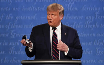 In this September 29, 2020, file photo, US President Donald Trump holds out his face mask during the first presidential debate  at Case Western University and Cleveland Clinic, in Cleveland, Ohio. (AP/Julio Cortez, File)