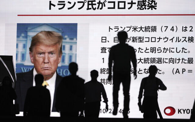 People walk past a screen showing the news report that US President Donald Trump has tested positive for the coronavirus, Friday, Oct. 2, 2020, in Tokyo. (AP Photo/Eugene Hoshiko) People walk past a screen showing the news report that US President Donald Trump has tested positive for the coronavirus, Friday, Oct. 2, 2020, in Tokyo. (AP Photo/Eugene Hoshiko)