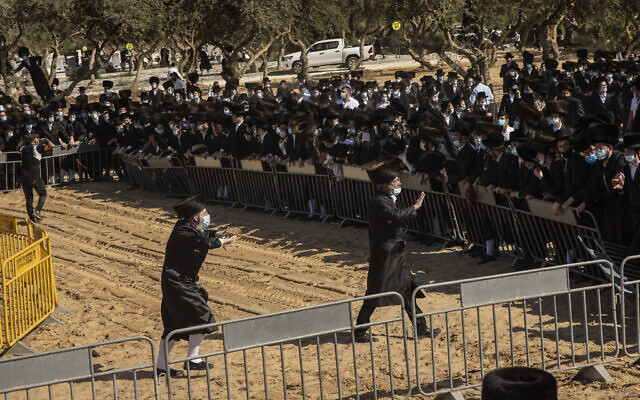 Ultra-Orthodox Jews try to enforce social distancing of mourners gathered for the funeral for Rabbi Mordechai Leifer, in the port city of Ashdod, Israel, Monday, Oct. 5, 2020. (AP Photo/Tsafrir Abayov)