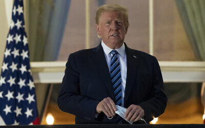 In this Monday, Oct. 5, 2020 photo, President Donald Trump removes his mask as he stands on the Blue Room Balcony upon returning to the White House in Washington, after leaving Walter Reed National Military Medical Center, in Bethesda, Md. Trump announced he tested positive for COVID-19 on Oct. 2. (AP Photo/Alex Brandon)