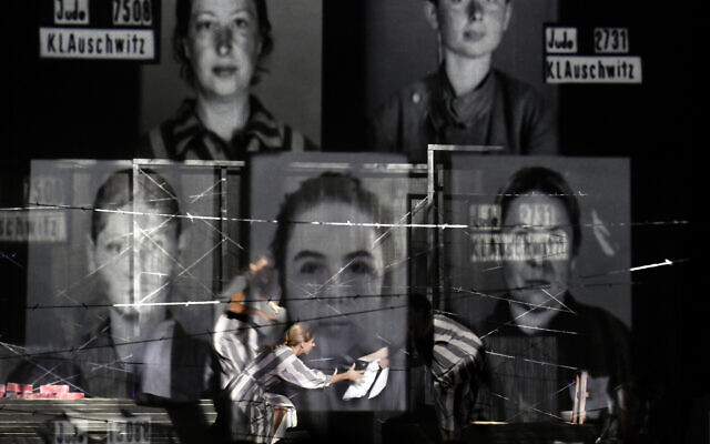 Portraits of Auschwitz death camp prisoners are displayed on a mesh as actresses of the Jewish State Theater perform during the premiere of the "The Beautiful Days of My Youth" play, based on the diary of Romanian Jewish Holocaust survivor Ana Novac, in Bucharest, October 16, 2020. (AP Photo/Andreea Alexandru)