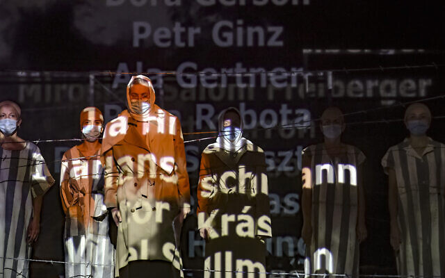 Names of victims scroll on a mesh at the Jewish State Theater as actresses perform wearing face masks for protection against COVID-19 infection, during the rehearsals for premiere of the "The Beautiful Days of My Youth" play, based on the diary of Romanian Jewish Holocaust survivor Ana Novac, in Bucharest, October 15, 2020. (AP Photo/Andreea Alexandru)
