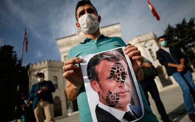 A man holds a photograph of France's President Emmanuel Macron, stamped with a shoe mark, during a protest against France in Istanbul, October 25, 2020. (AP Photo/Emrah Gurel)