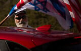 An Israeli supporter of the reelection of US President Donald Trump waves American and Israeli flags from a car at a rally outside of the US Embassy, in Jerusalem, Tuesday, Oct. 27, 2020. (AP Photo/Maya Alleruzzo)
