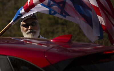 An Israeli supporter of the reelection of US President Donald Trump waves American and Israeli flags from a car at a rally outside of the US Embassy, in Jerusalem, Tuesday, Oct. 27, 2020. (AP Photo/Maya Alleruzzo)
