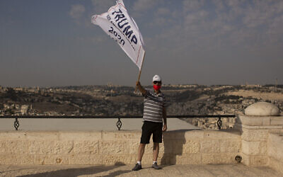 An Israeli supporter of US President Donald Trump waves a campaign flag at a rally for his re-election, on a promenade overlooking Jerusalem, October 27, 2020. (Maya Alleruzzo/AP)