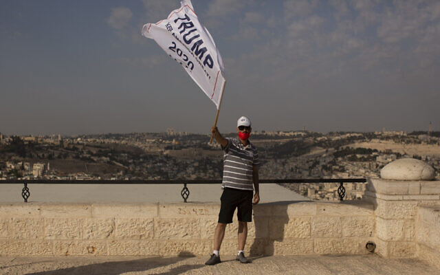 An Israeli supporter of US President Donald Trump waves a campaign flag at a rally for his re-election, on a promenade overlooking Jerusalem, October 27, 2020. (Maya Alleruzzo/AP) An Israeli supporter of US President Donald Trump waves a campaign flag at a rally for his re-election, on a promenade overlooking Jerusalem, October 27, 2020. (Maya Alleruzzo/AP)