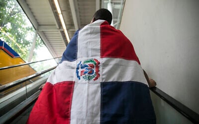 Illustrative: A man wears a Dominican flag on his way out of the subway station to march with the Green Movement in Santo Domingo, Dominican Republic, July 16, 2017. (AP Photo/Tatiana Fernandez)