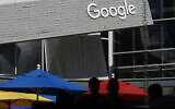 People walk by a Google sign on the campus in Mountain View, California, on September 24, 2019. (AP Photo/ Jeff Chiu, File)