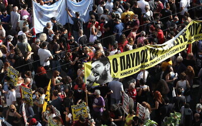 People holding a banner depicting Greek rap singer Pavlos Fyssas, who was stabbed and killed by a supporter of the extreme right Golden Dawn party in 2013, gather for a protest outside a court ahead of verdict in the case, in Athens, October 7, 2020. (AP Photo/Yorgos Karahalis)