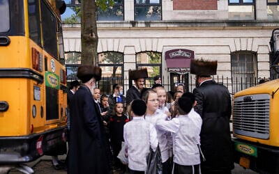 Illustrative: Members of the Orthodox Jewish community wait for school buses to collect them in the Borough Park neighborhood of the Brooklyn borough of New York, October 8, 2020. (AP Photo/John Minchillo)