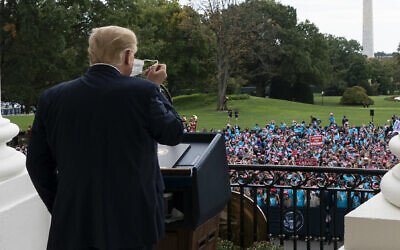 President Donald Trump removes his mask before speaking from the Blue Room Balcony of the White House to a crowd of supporters, Saturday, Oct. 10, 2020, in Washington. (AP/Alex Brandon)