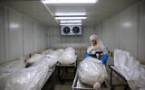 A worker from 'Hevra Kadisha,' Israel's official Jewish burial society, prepares bodies at a special morgue for COVID-19 victims in Holon, near Tel Aviv, October 12, 2020. (AP Photo/Oded Balilty)