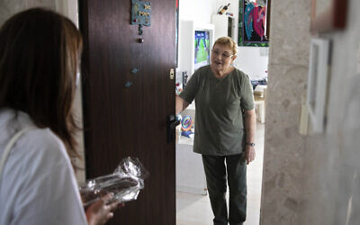 Israeli volunteer Sharon Yaron, left, brings a cake to 85-year-old Holocaust survivor Sara Weinsten during a visit to her house in Yavne, Israel, October 8, 2020. (AP Photo/Sebastian Scheiner)