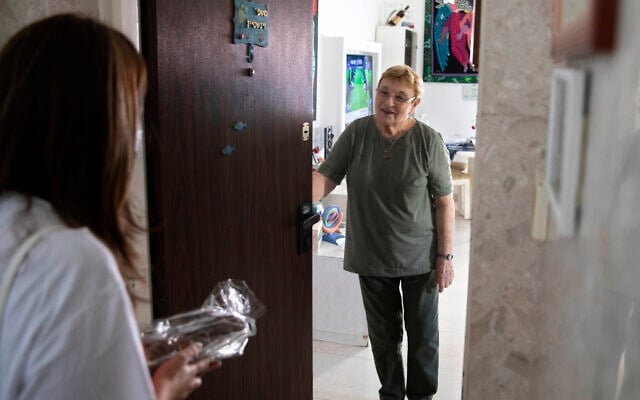 Israeli volunteer Sharon Yaron, left, brings a cake to 85-year-old Holocaust survivor Sara Weinsten during a visit to her house in Yavne, Israel, October 8, 2020. (AP Photo/Sebastian Scheiner) Israeli volunteer Sharon Yaron, left, brings a cake to 85-year-old Holocaust survivor Sara Weinsten during a visit to her house in Yavne, Israel, October 8, 2020. (AP Photo/Sebastian Scheiner)