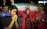In this July 14, 2015, photo, an Iranian woman holds up a national flag as people celebrate a landmark nuclear deal, in Tehran, Iran. (AP Photo/Ebrahim Noroozi)