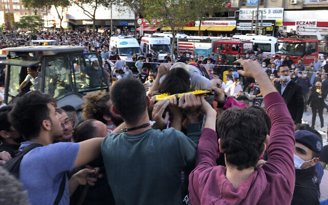 Rescue workers and local people carry a wounded person found in the debris of a collapsed building, in Izmir, Turkey, Friday, Oct. 30, 2020, after a strong earthquake in the Aegean Sea has shaken Turkey and Greece..(AP Photo/Ismail Gokmen)