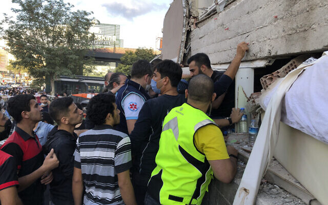 Rescue workers and local people try to reach residents trapped in the debris of a collapsed building, in Izmir, Turkey, Friday, Oct. 30, 2020, after a strong earthquake in the Aegean Sea has shaken Turkey and Greece. (AP Photo/Ismail Gokmen)