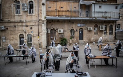 Illustrative: Ultra-Orthodox Jews from the Karlin (Hasidic dynasty) praying according to the social distancing rules outside their synagogue in Jerusalem on August 10, 2020 (Yonatan Sindel/Flash90)
