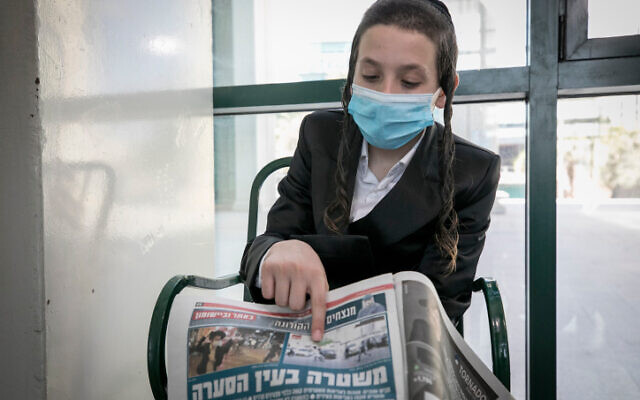 A boy who was seen on video getting hit by a bucket hurled by a cop in Beitar Illit a day earlier points to a copy of Israel Hayom with a picture of the incident, while in Jerusalem on October 5, 2020. (Olivier Fitoussi/Flash90) A boy who was seen on video getting hit by a bucket hurled by a cop in Beitar Illit a day earlier points to a copy of Israel Hayom with a picture of the incident, while in Jerusalem on October 5, 2020. (Olivier Fitoussi/Flash90)