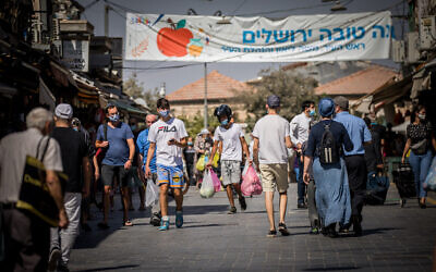 People wearing face masks shop at the Mahane Yehuda Market in Jerusalem on October 7, 2020, during a nationwide lockdown to prevent the spread of COVID-19 (Yonatan Sindel/Flash90)