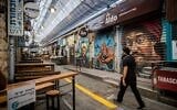 People wearing face masks walk through the largely shuttered Mahane Yehuda Market in Jerusalem on October 7, 2020. (Yonatan Sindel/Flash90)