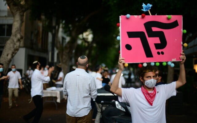 A man protests against Prime Minister Benjamin Netanyahu during Simchat Torah celebrations in Tel Aviv on October 10, 2020 (Tomer Neuberg/Flash90) A man protests against Prime Minister Benjamin Netanyahu during Simchat Torah celebrations in Tel Aviv on October 10, 2020 (Tomer Neuberg/Flash90)