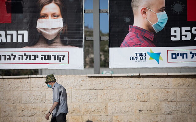 People walk past a billboard posted by the Health Ministry instructing people to wear face masks, in Jerusalem on October 11, 2020. (Yonatan Sindel/Flash90) People walk past a billboard posted by the Health Ministry instructing people to wear face masks, in Jerusalem on October 11, 2020. (Yonatan Sindel/Flash90)