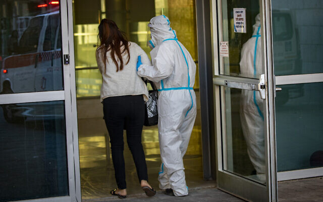 A Magen David Adom paramedic wearing protective equipment escorts a patient to the coronavirus unit at Hadassah Hospital Ein Karem in Jerusalem on October 19, 2020. (Olivier Fitoussi/Flash90) A Magen David Adom paramedic wearing protective equipment escorts a patient to the coronavirus unit at Hadassah Hospital Ein Karem in Jerusalem on October 19, 2020. (Olivier Fitoussi/Flash90)
