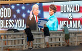 Backdropped by a billboard supporting US President Donald Trump and first lady Melania Trump, people wave flags on a bridge during a protest against Prime Minister Benjamin Netanyahu in Tel Aviv, October 3, 2020. (AP Photo/Oded Balilty)