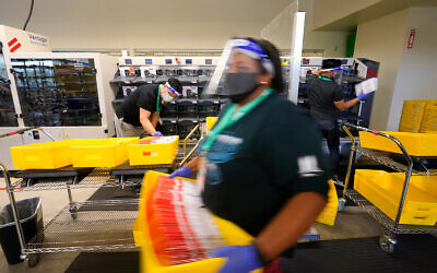 Election workers sort returned ballots at the King County Elections office in Renton, Washington, Oct. 20, 2020. (AP Photo/Elaine Thompson)