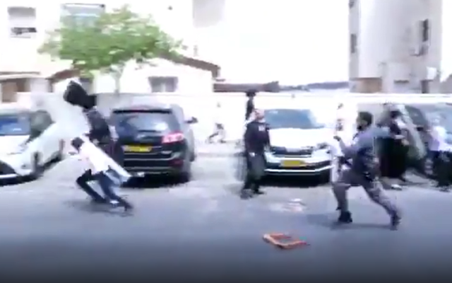 A police officer (R) throws a bucket at a boy during a protest in Beitar Illit, October 4, 2020. (Screenshot: Twitter) A police officer (R) throws a bucket at a boy during a protest in Beitar Illit, October 4, 2020. (Screenshot: Twitter)