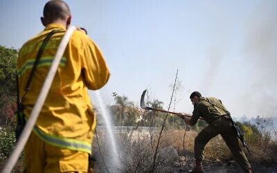 A firefighters and a soldier work together against a fire at the Kfar HaOranim settlemet in the West Bank, amid a rash of blazes throughout the country, October 9, 2020 (IDF)