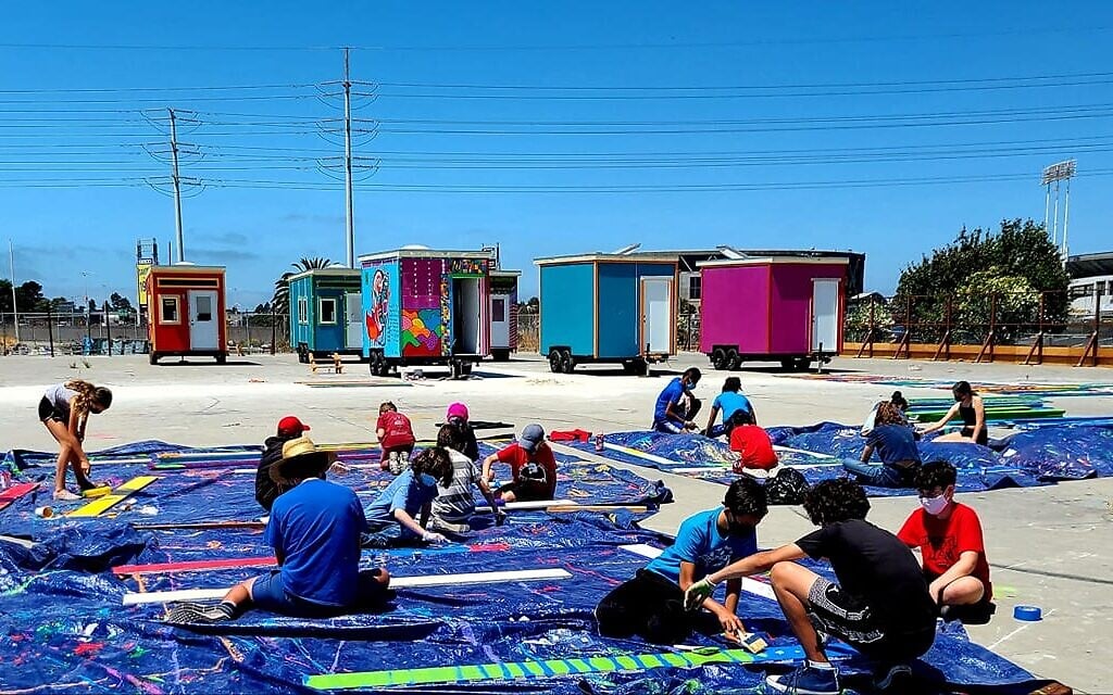 Campers from Camp Kee Tov, Congregation Beth El's Jewish summer camp, paint planks for the perimeter fence at the YSA Tiny House Village in Oakland, California on August 4, 2020. (courtesy Sally Hindman)