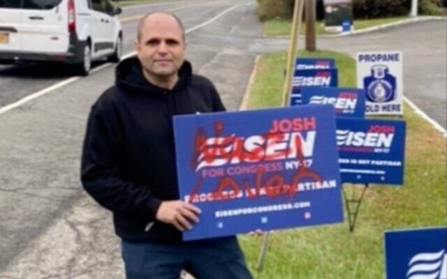 Congressional candidate Josh Eisen holds a campaign sign tagged with anti-Semitic graffiti. (Screenshot from News12 via JTA) Congressional candidate Josh Eisen holds a campaign sign tagged with anti-Semitic graffiti. (Screenshot from News12 via JTA)