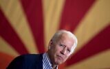 Joe Biden pauses while speaking to supporters in front of an Arizona state flag, at the United Brotherhood of Carpenters and Joiners of America's training center, on October 8, 2020, in Phoenix. (Brendan Smialowski/AFP)