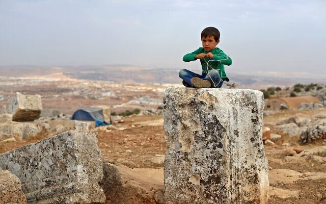 A Syrian child plays on November 1, 2020 at a makeshift camp of Syrians displaced by war at the UNESCO-listed site of Baqirha not far from the Turkish border, in a region of northwest Syria filled with abandoned Roman and Byzantine settlements (Abdulaziz Ketaz / AFP)