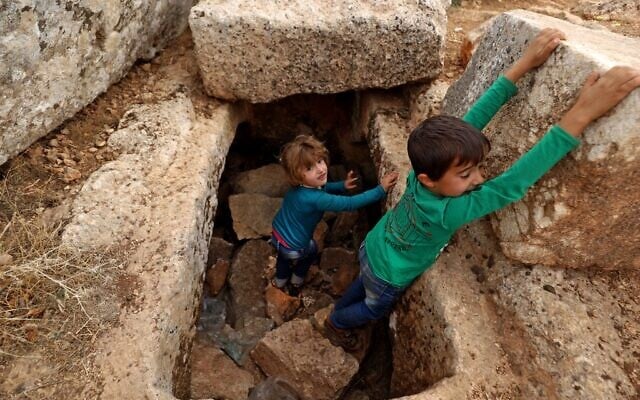 Syrian children play amid ruins on November 1, 2020 at the UNESCO-listed site of Baqirha not far from the Turkish border, in a region of northwest Syria filled with abandoned Roman and Byzantine settlements (Abdulaziz Ketaz / AFP)