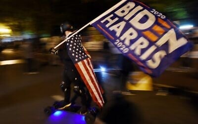 A man waves a Biden-Harris flag as demonstrators gather at Black Lives Matter plaza across from the White House on election night in Washington, DC on November 3, 2020. (Olivier DOULIERY / AFP)