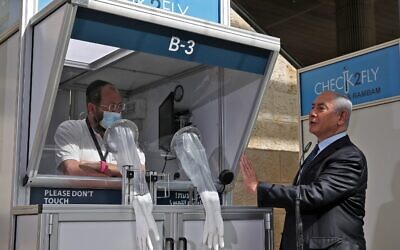 Mask-clad Prime Minister Benjamin Netanyahu speaks with a coronavirus swab sampling booth technician during the inauguration of a COVID-19 coronavirus rapid testing center at Ben Gurion International Airport in Lod on November 9, 2020. (ATEF SAFADI / POOL / AFP)