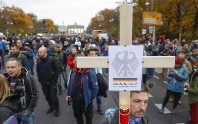 A demonstrator carries a cross with the inscription "German Constitution Law" during a protest against measures imposed by the German government to limit the spread of the coronavirus, on November 18, 2020 near the Brandenburg Gate in Berlin. (Odd ANDERSEN / AFP)