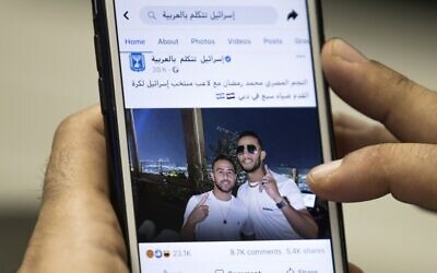A man in Cairo holds a phone showing a picture of Egyptian singer Mohamed Ramadan posted by the official Facebook page of the State of Israel in Arabic showing Ramadan, right, hugging Israeli soccer player Diaa Sabia in Dubai, November 22, 2020. (Khaled Desouki/AFP)