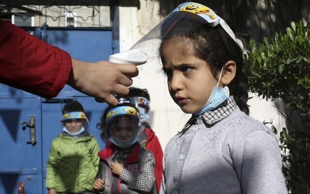Palestinian children have their temperature checked as they arrive at a kindergarten in Gaza city while wearing face shields due to the COVID-19 pandemic, on November 23, 2020. (MOHAMMED ABED / AFP) Palestinian children have their temperature checked as they arrive at a kindergarten in Gaza city while wearing face shields due to the COVID-19 pandemic, on November 23, 2020. (MOHAMMED ABED / AFP)