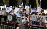 Members of the Jewish Ethiopian community hold up photographs of their relatives outside the Prime Minister's Office in Jerusalem on November 25, 2020, during a demonstration demanding to bring thousands of their remaining brethren from Ethiopia to Israel. (Menahem Kahana/AFP)