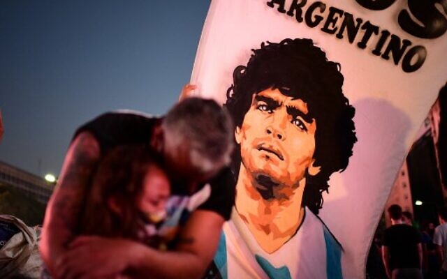 A father and her daughter, fans of Argentinian football legend Diego Maradona, mourn as they gather by the Obelisk to pay homage on the day of his death in Buenos Aires, on November 25, 2020. (Photo by RONALDO SCHEMIDT / AFP) A father and her daughter, fans of Argentinian football legend Diego Maradona, mourn as they gather by the Obelisk to pay homage on the day of his death in Buenos Aires, on November 25, 2020. (Photo by RONALDO SCHEMIDT / AFP)